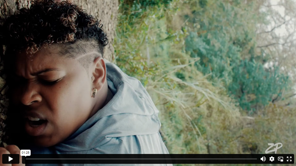 A video thumbnail of a Black woman with short black hair, fallen on the ground outdoors, looking hurt.