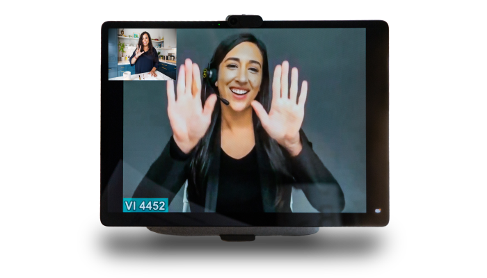 The image focuses on a tablet with an interpreter, wearing black clothes with a black background, signing and smiling.