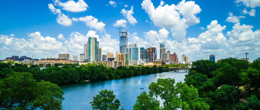 Gorgeous green summer view above tree tops with drone view Travel destination town lake , water , and bridges Austin Texas growing downtown skyline cityscape aerial drone view tower Modern urban skyscraper rises above the rest Green summer Texas landscape high above Austin Texas growing downtown skyline cityscape aerial drone view from west side of Austin